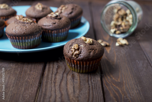 on a wooden background is a blue plate with chocolate cakes and nuts.