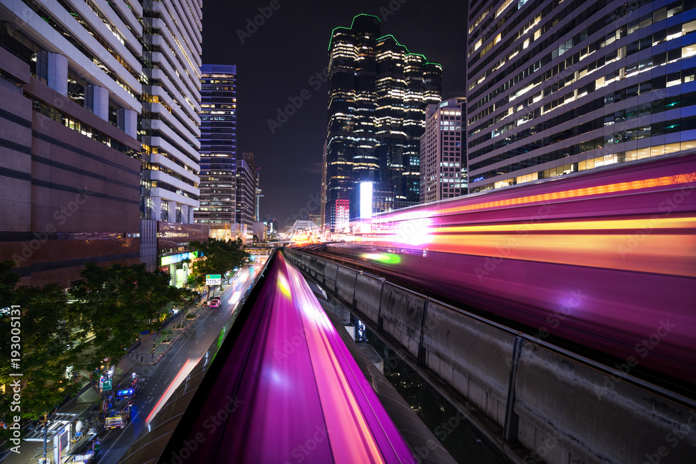 Obraz premium abstract light tail of sky train in urban cityscape at night
