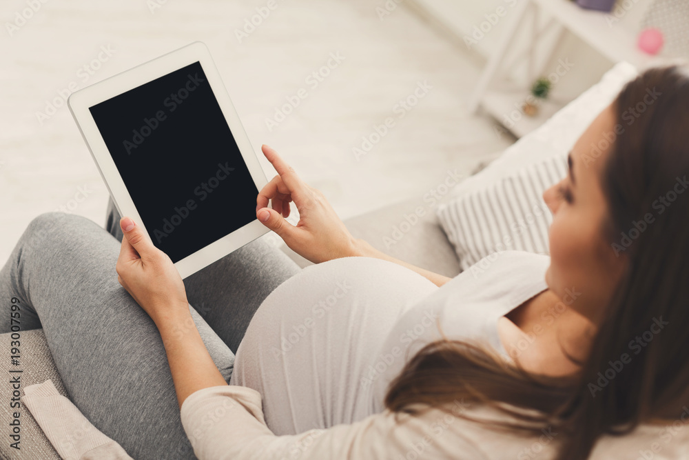 Happy pregnant woman using digital tablet at home