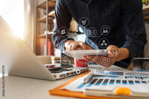  businessman hand working with laptop computer, tablet and smart phone in modern office with virtual icon diagram at modernoffice in morning light 