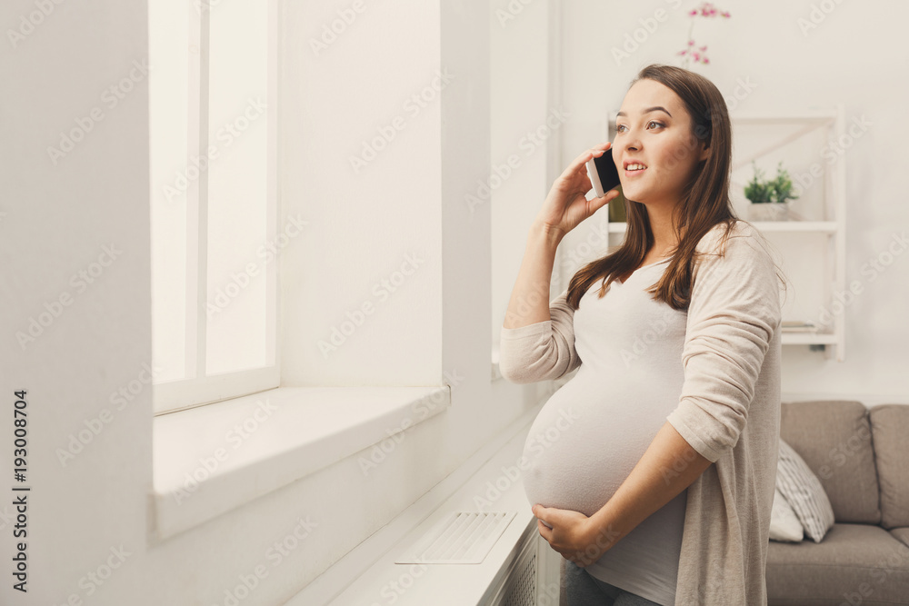 Smiling pregnant woman talking on her smartphone Smiling pregnant woman talking on her smartphone