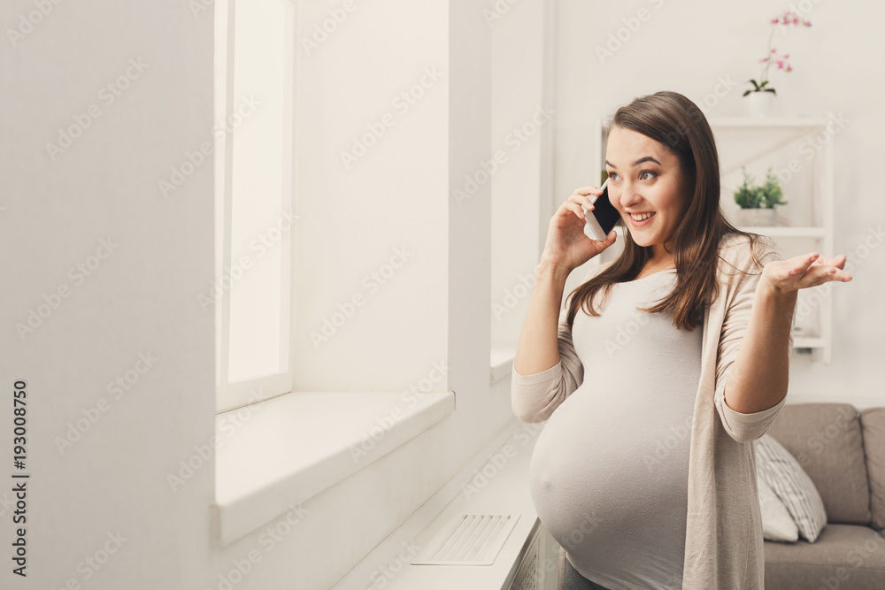 Smiling pregnant woman talking on her smartphone Smiling pregnant woman talking on her smartphone