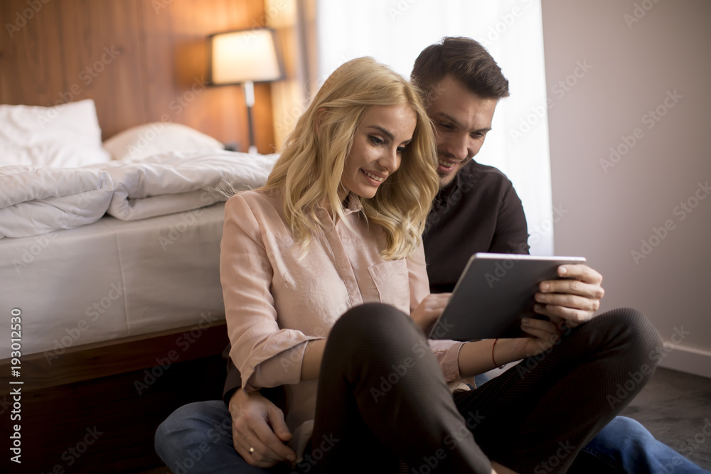 Happy couple sitting on the floor with tablet