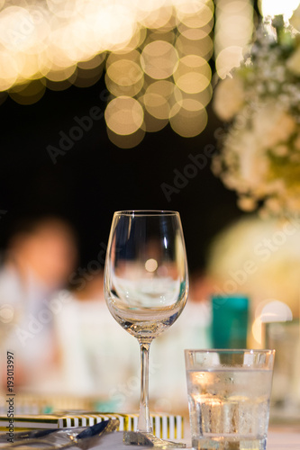 clear wine glass on table in dinner table with beautiful bokeh in background.