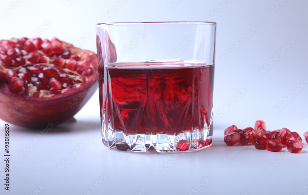 Glass with pomegranate juice Pomegranate seeds and Beautiful ripe pomegranate on white background with place for copy space. Glass with pomegranate juice Pomegranate seeds and Beautiful ripe pomegranate on white background with place for copy space.