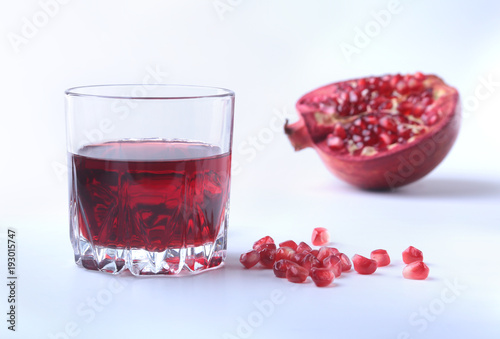 Glass with pomegranate juice Pomegranate seeds and Beautiful ripe pomegranate on white background with place for copy space. photo