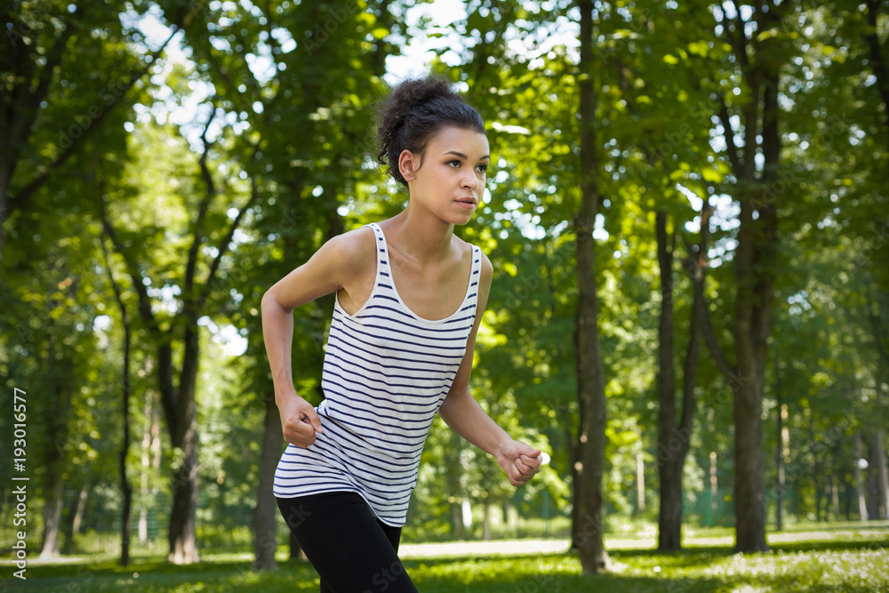 Young woman running in green park, copy space Young woman running in green park, copy space