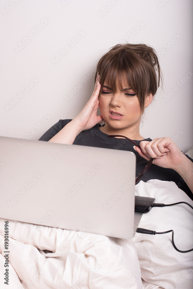 young woman in bed having problems with her laptop young woman in bed having problems with her laptop
