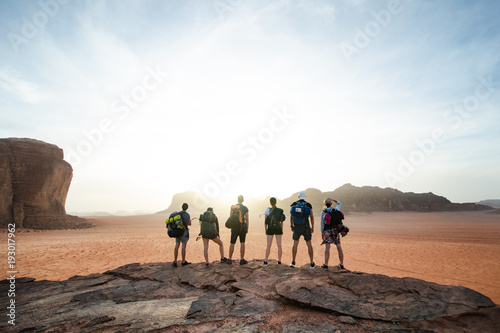 Tourist friends on a top of mountains in a desert. Sunset view. Nature. Tourist people enjoy a moment in a nature. Wadi rum national park - Jordan 