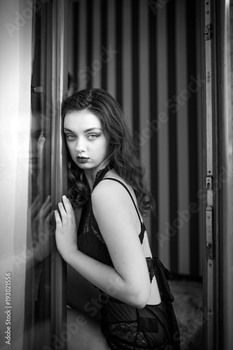 Young sexy woman in black lingerie standing in the doorway. Black and white photography