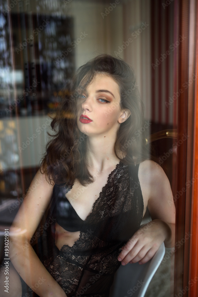 Young sexy woman in black lingerie poses outside the window. Reflection effects Young sexy woman in black lingerie poses outside the window. Reflection effects