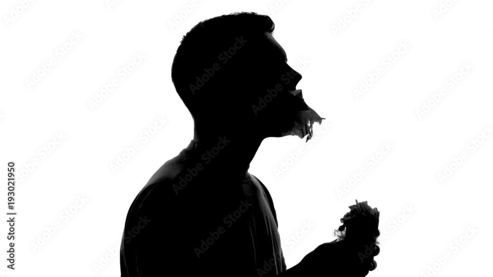 Hungry man silhouette with huge appetite biting and chewing greasy fast food Hungry man silhouette with huge appetite biting and chewing greasy fast food