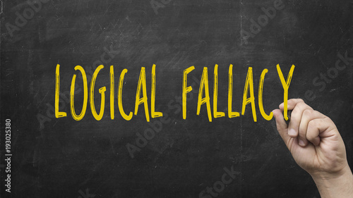 Hand writing logical fallacy text on blackboard