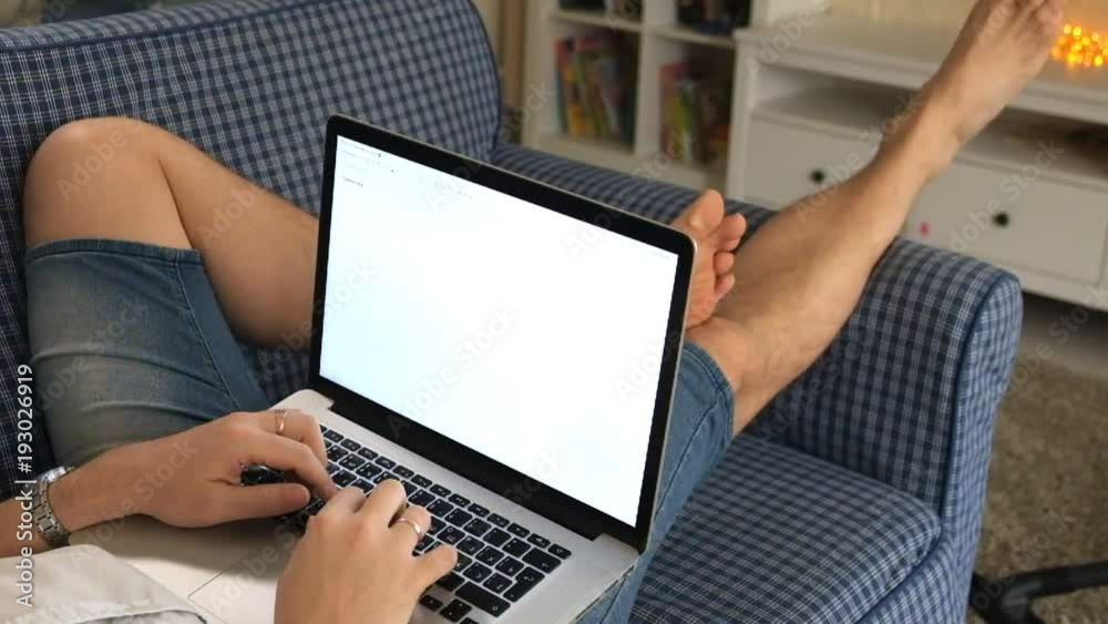 man lying on sofa in room working behind laptop man lying on sofa in room working behind laptop
