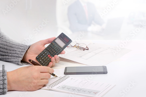 Kobieta w biurze trzyma w dłoniach kalkulator i wieczne piuro.