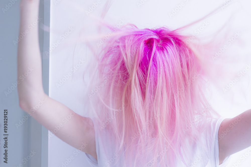 pink hair woman is roughing her hair by hands in the air pink hair woman is roughing her hair by hands in the air