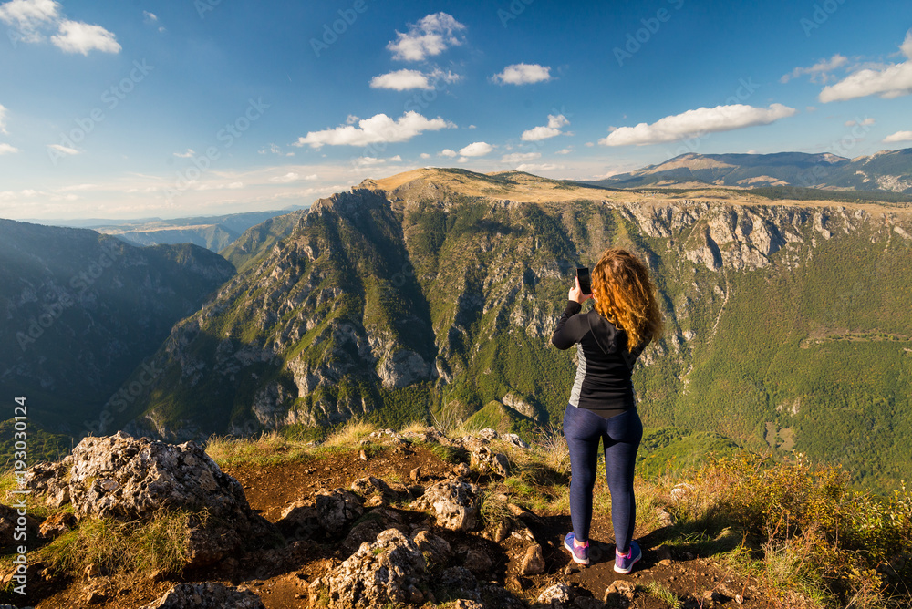 Young woman is taking a photo of the mountains in the Durmitor national park in Montenegro