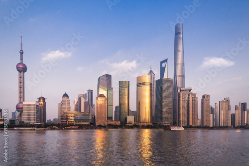 Beautiful cityscape with glass skyscrapers standing along the Huangpu River against the backdrop of the setting sun