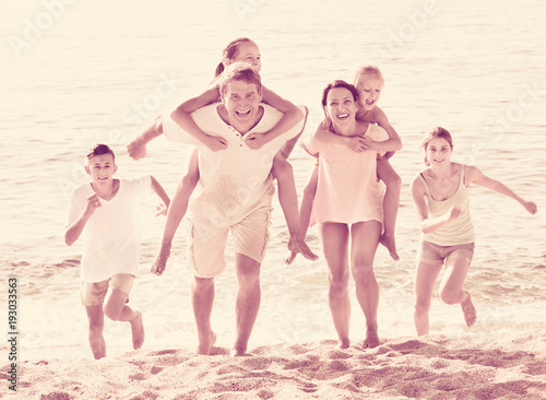 Large family happily running and carrying kids on parents back