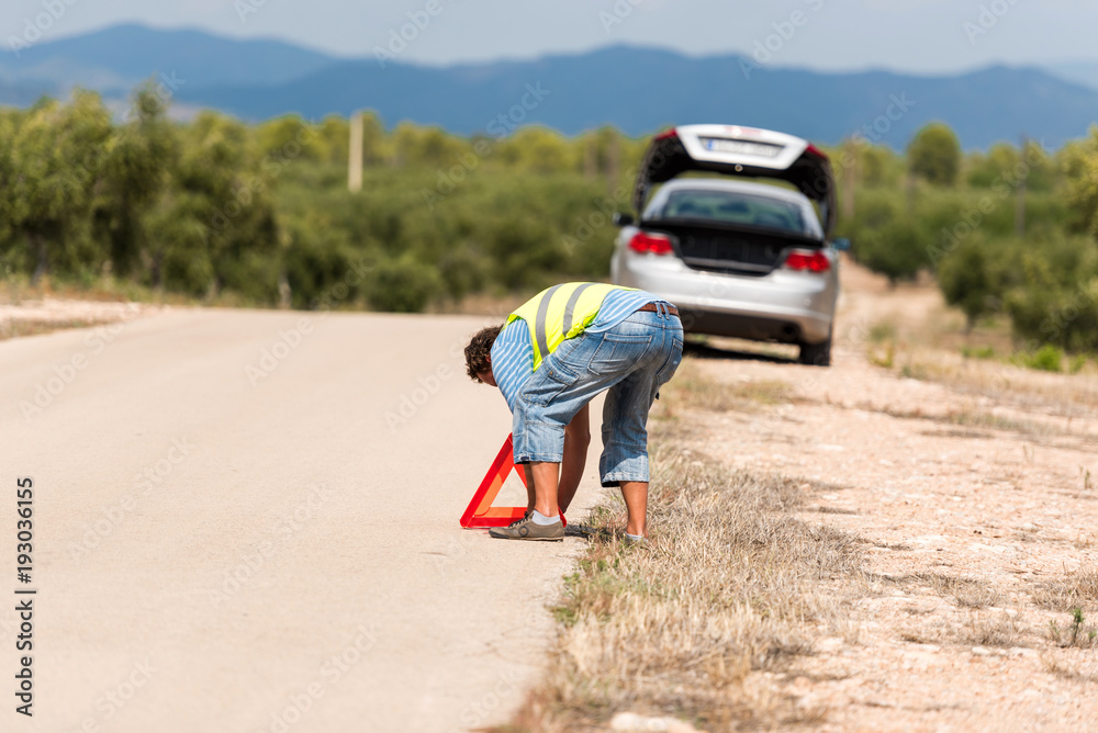 A man on the road sets an emergency sign, Tarragona, Catalunya, Spain. Copy space for text. A man on the road sets an emergency sign, Tarragona, Catalunya, Spain. Copy space for text.