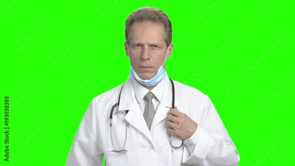 Upset male doctor on green screen. Serious mature medical doctor adjusting his stethoscope on chrome key background. Caucasian middle aged doctor looking at camera. Medicine and healthcare concept. Upset male doctor on green screen. Serious mature medical doctor adjusting his stethoscope on chrome key background. Caucasian middle aged doctor looking at camera. Medicine and healthcare concept.
