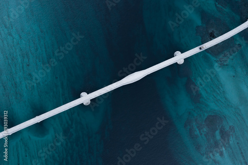 Aerial shot of a bridge over sea strait. Visible depth with blue and green colours near Tromso. Sommaroy, Norway