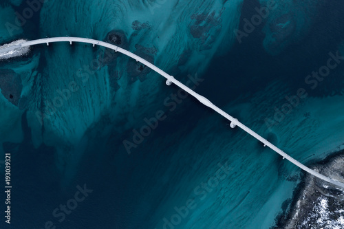 Fototapeta Naklejka Na Ścianę i Meble -  Aerial shot of a bridge over sea strait. Visible depth with blue and green colours near Tromso. Sommaroy, Norway
