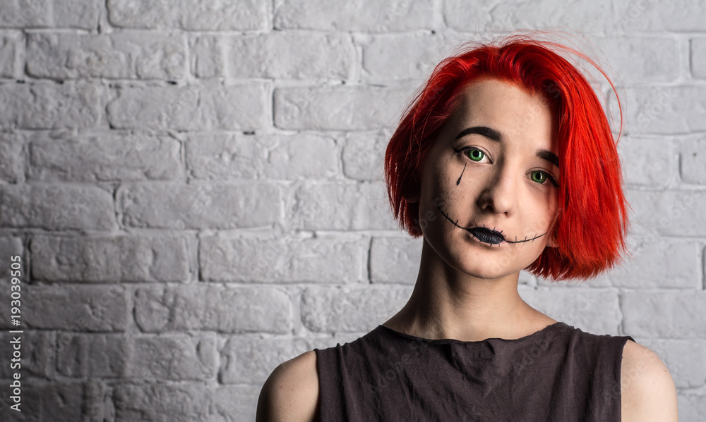 Portrait. Teenage girl with bright red hair at the white wall. On the face of the girl makeup.
Portrait. Teenage girl with bright red hair at the white wall. On the face of the girl makeup.