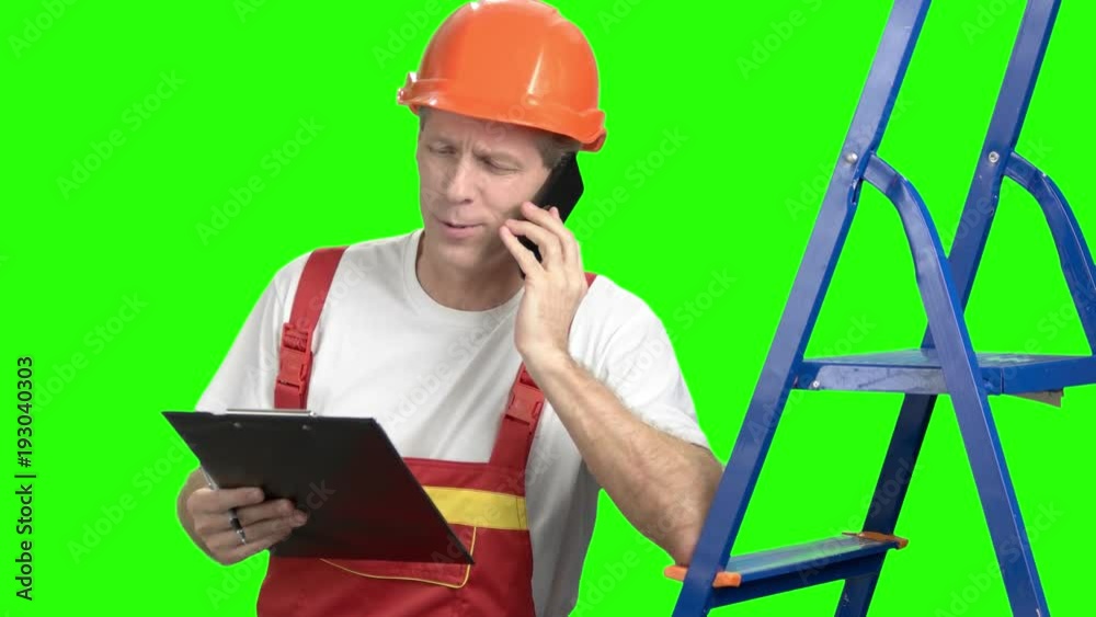 Architect talking on cell phone, green screen. Cheerful foreman talking on mobile phone while looking at clipboard, chroma key background. Architect talking on cell phone, green screen. Cheerful foreman talking on mobile phone while looking at clipboard, chroma key background.
