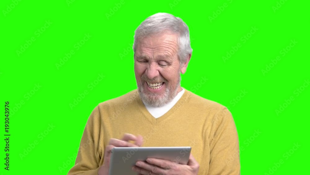 Funny senior man using pc tablet. Happy smiling aged man with digital tablet on chroma key background. Elderly man play game on computer tablet. Funny senior man using pc tablet. Happy smiling aged man with digital tablet on chroma key background. Elderly man play game on computer tablet.