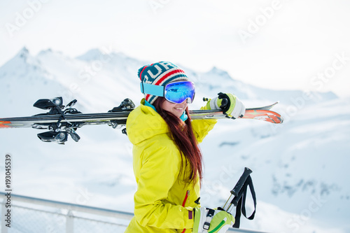 Photo of smiling sports woman with skis on her shoulder against
