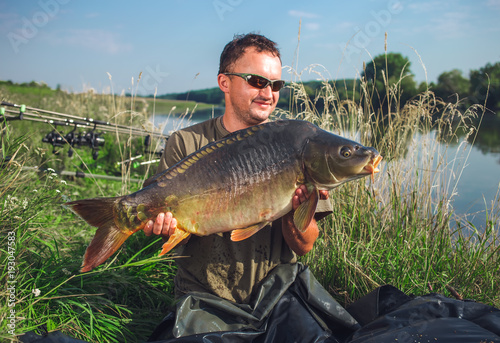 Happy angler with carp fishing trophy