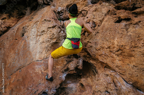 female rock climber climbing on steep cliff
