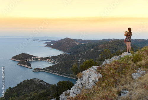 Fototapeta Naklejka Na Ścianę i Meble -  A female turist makes a photo on a smartphone on the island of Lastovo, Croatia