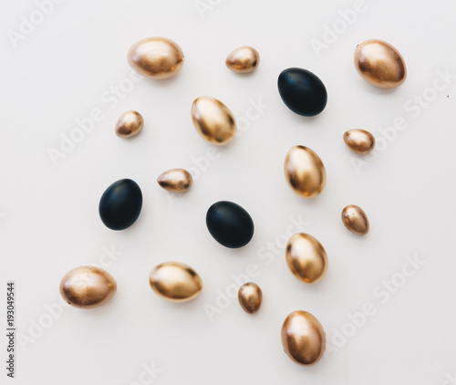 Black and gold eggs over white background. Minimal flat lay
