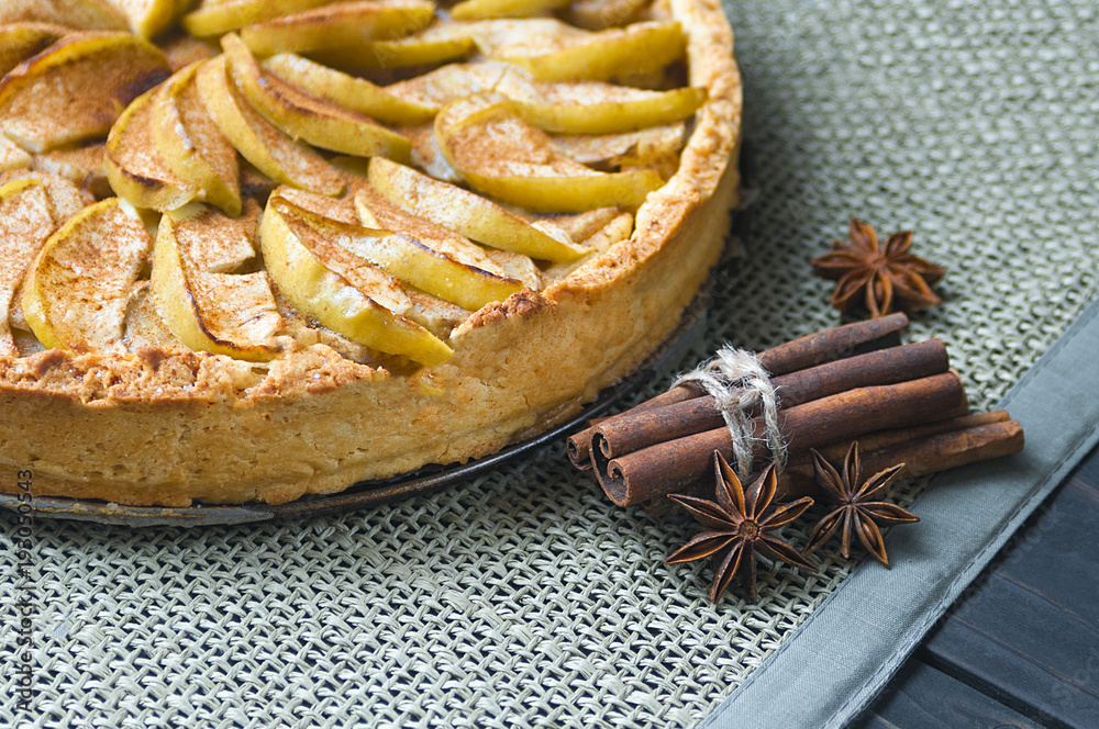 Fototapeta premium Baked apple pie, tart with cinnamon and star anice with sackcloth on dark wooden background.
