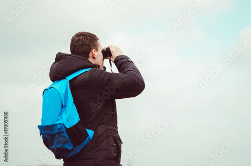 The traveler looks through binoculars. a backpack on the shoulders.