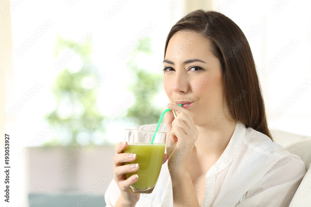 Girl drinking a vegetable green juice looking at you Girl drinking a vegetable green juice looking at you