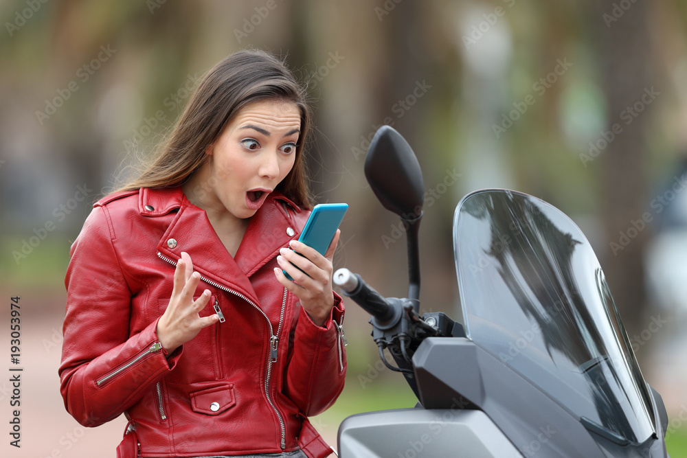 Fototapeta premium Zdziwiony motocyklista czytający ekscytujące wiadomości on-line