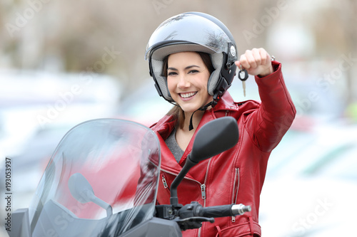 Happy motorbiker showing keys on her new motorbike