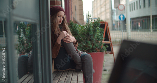 Beautiful sad anxious woman sitting alone in a city.