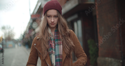 Beautiful sad anxious woman standing in a city street.