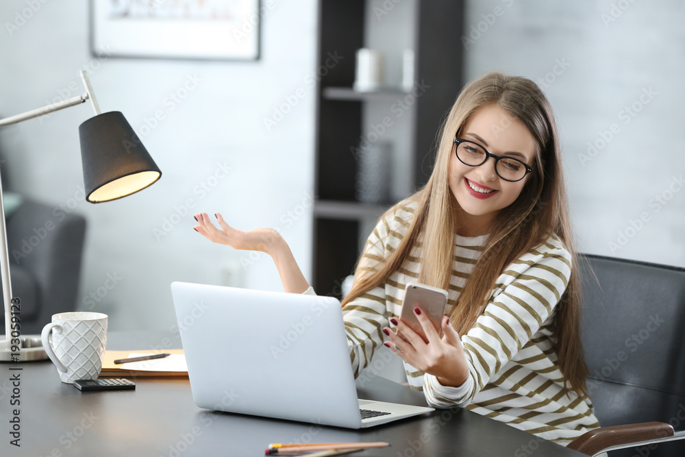 Beautiful smiling woman using her mobile phone in office Beautiful smiling woman using her mobile phone in office