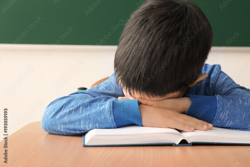 Sleeping little boy tired of doing homework in classroom Sleeping little boy tired of doing homework in classroom