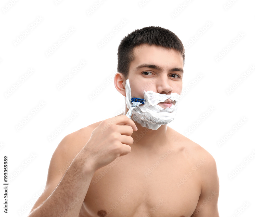 Handsome young man shaving against white background