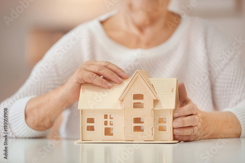 Senior woman with house model at table. Home care concept