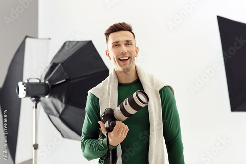 Young photographer with camera in studio. Small business owner