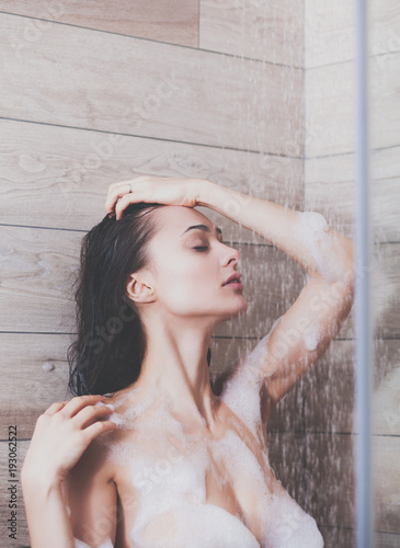 Young beautyful woman under shower in bathroom.