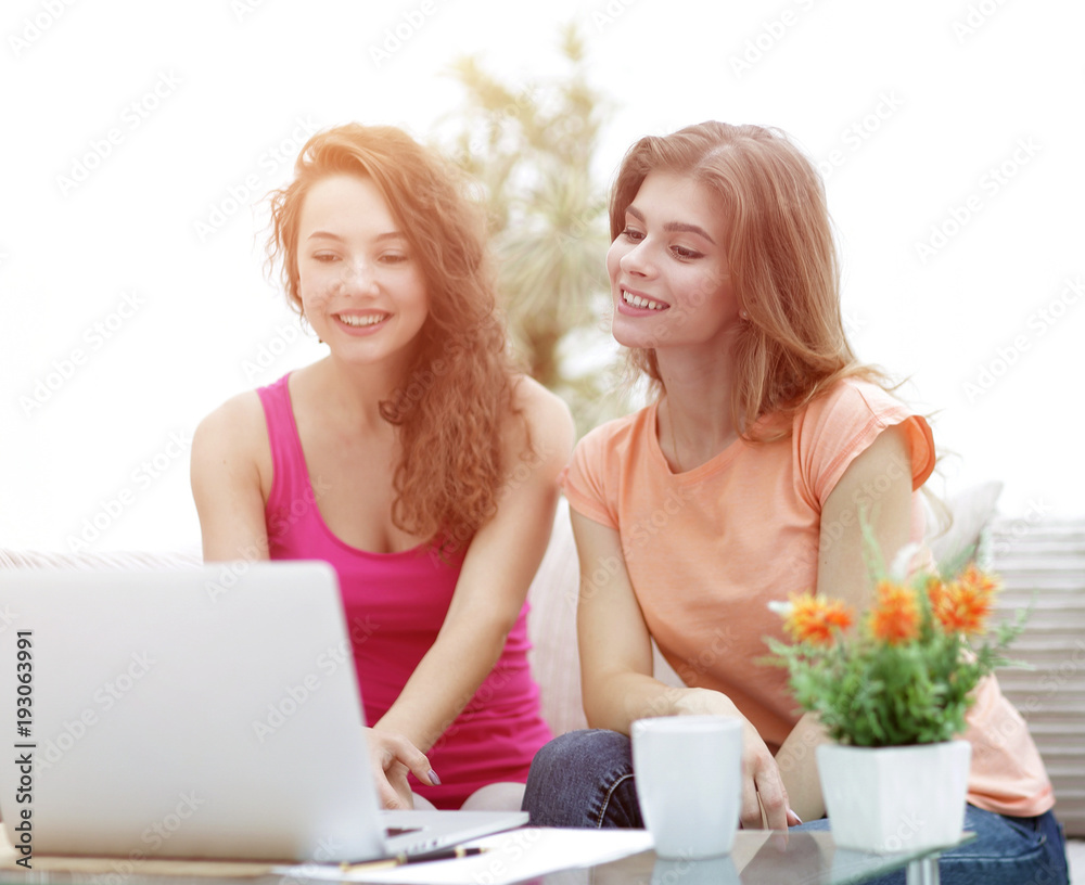 two student girls looking at laptop screen while sitting on the two student girls looking at laptop screen while sitting on the