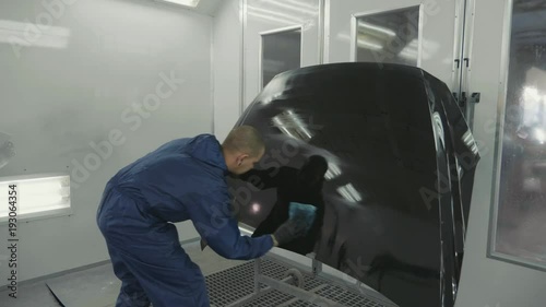 Serviceman preparing a car bodykit for painting in a workshop photo